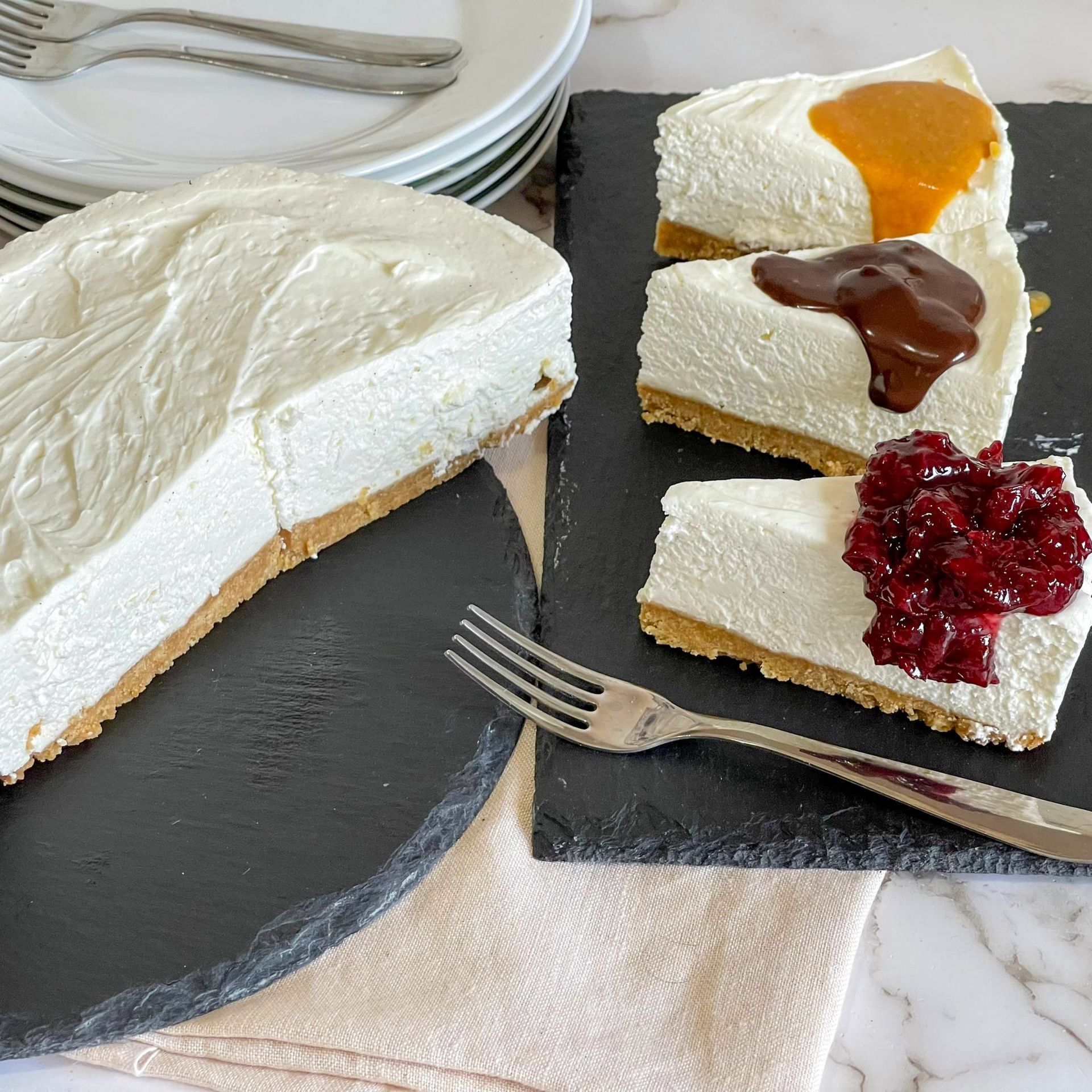 Tre fette di cheesecake su un tagliere con una forchetta