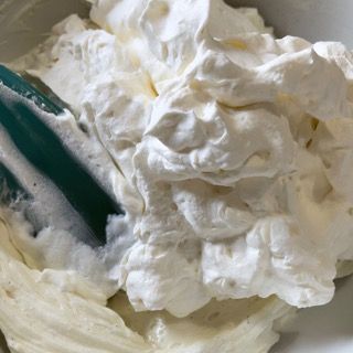 Una ciotola di panna montata con una spatola dentro.