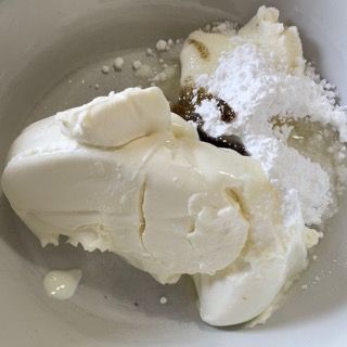 Una ciotola bianca piena di formaggio cremoso e zucchero a velo