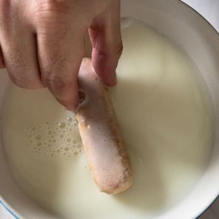 Una persona sta immergendo una ciambella in una ciotola di latte.