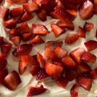 Una torta con fragole e panna montata sopra