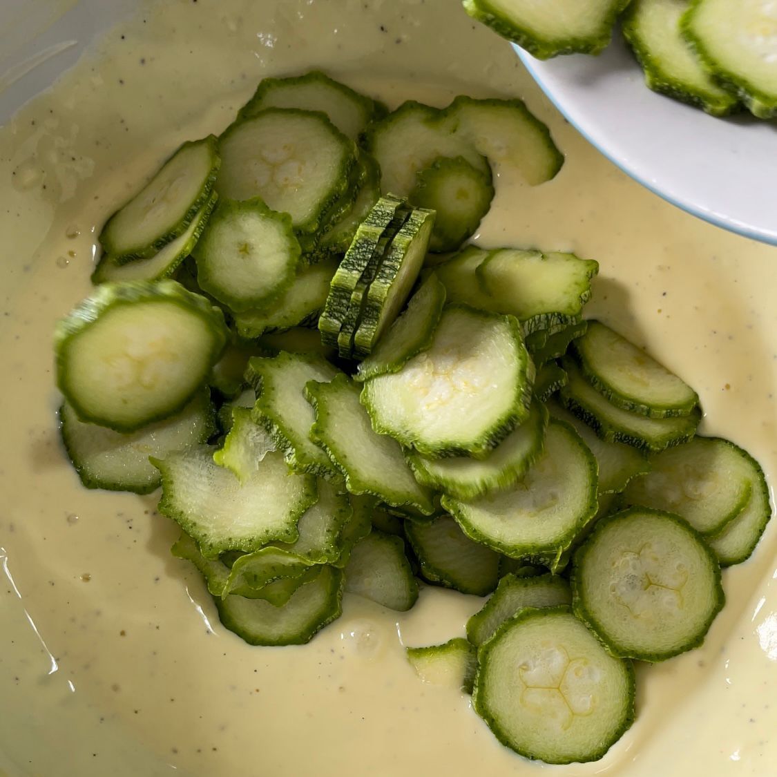 I cetrioli affettati vengono versati in una ciotola di salsa