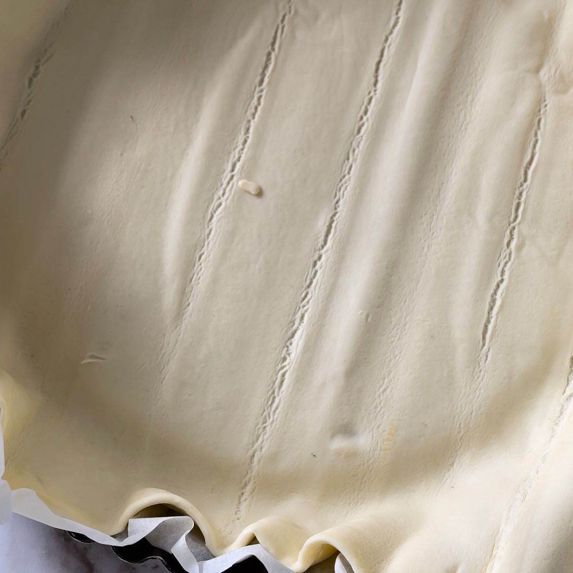 Primo piano di una crosta di torta in una teglia su un tavolo.