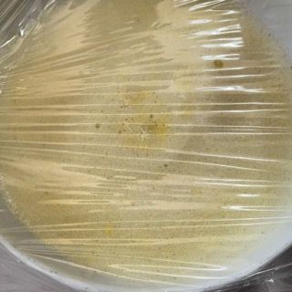 Un piatto bianco ricoperto di pellicola trasparente su un tavolo.