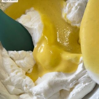 Un cucchiaio verde è in una ciotola di panna montata e liquido giallo