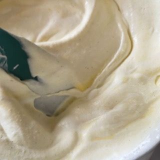 Primo piano di una ciotola di panna montata con una spatola dentro.