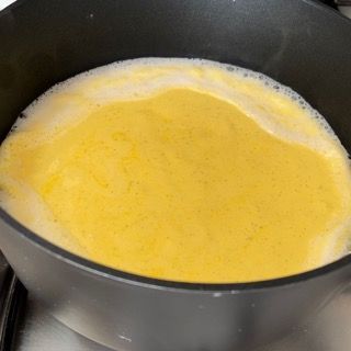 Una pentola piena di liquido giallo sta cuocendo sul fornello.
