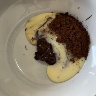 Una ciotola bianca piena di salsa al cioccolato e cacao in polvere
