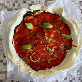 Una pizza con salsa di pomodoro e foglie di basilico sopra