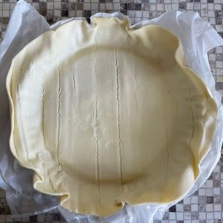 Una crosta di torta appoggiata su un pezzo di carta oleata
