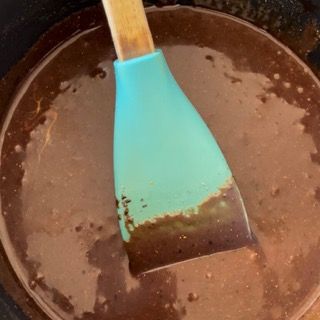 Una spatola blu è in una pentola di salsa al cioccolato