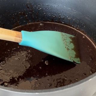 Una spatola verde è in una pentola di liquido marrone