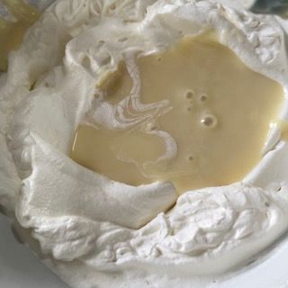 Primo piano di una ciotola di panna montata contenente un liquido giallo.