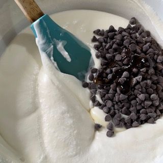 Una ciotola di yogurt con gocce di cioccolato e una spatola