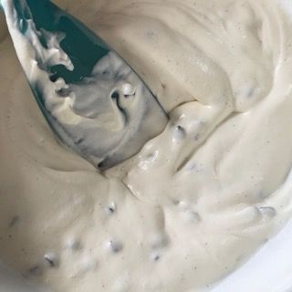 Un primo piano di una ciotola di salsa ranch con un cucchiaio dentro.