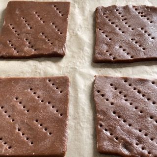 Quattro cracker al cioccolato sono appoggiati su un pezzo di carta oleata