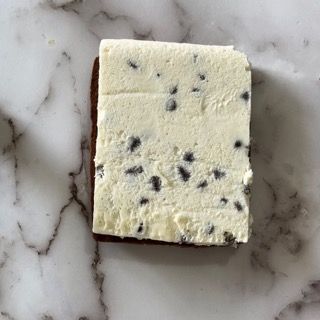 Un pezzo di gelato con gocce di cioccolato su una superficie di marmo.