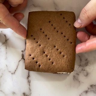 Una persona tiene in mano un gelato al cioccolato su una superficie di marmo.