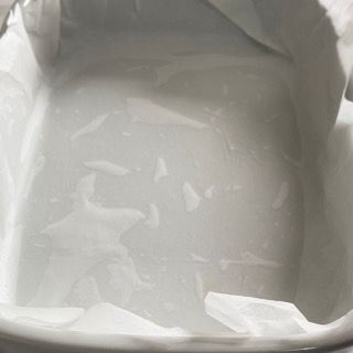 Una ciotola bianca piena d'acqua e un pezzo di carta oleata.