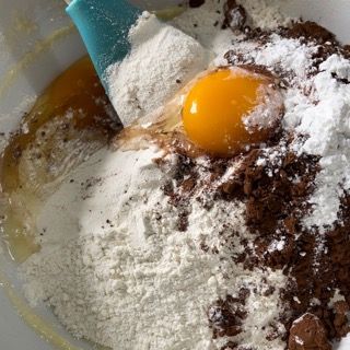 Una ciotola piena di farina, uova e cioccolato con una spatola dentro