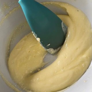 Una spatola blu è in una ciotola di liquido giallo.