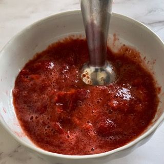 Una ciotola di salsa di fragole con un frullatore dentro