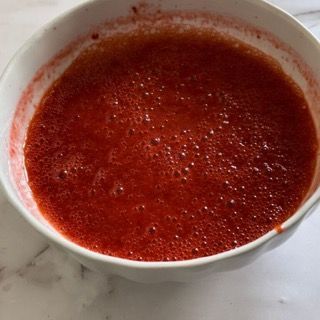 Una ciotola bianca piena di liquido rosso su un tavolo