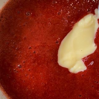 Un primo piano di una ciotola di salsa di fragole con un cucchiaio dentro