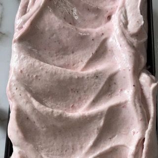 Primo piano di un contenitore di gelato rosa su un tavolo.