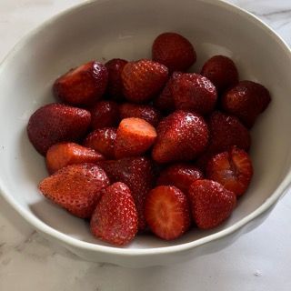 Una ciotola bianca piena di fragole su un tavolo