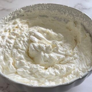 Una ciotola di panna montata è appoggiata su un tavolo.