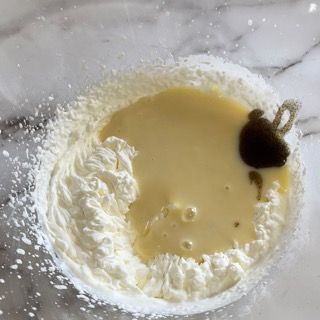 Primo piano di una ciotola di panna montata e liquido su un tavolo.