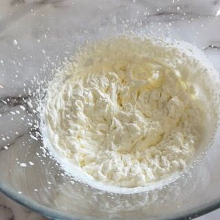 Primo piano di una ciotola di panna montata su un tavolo.