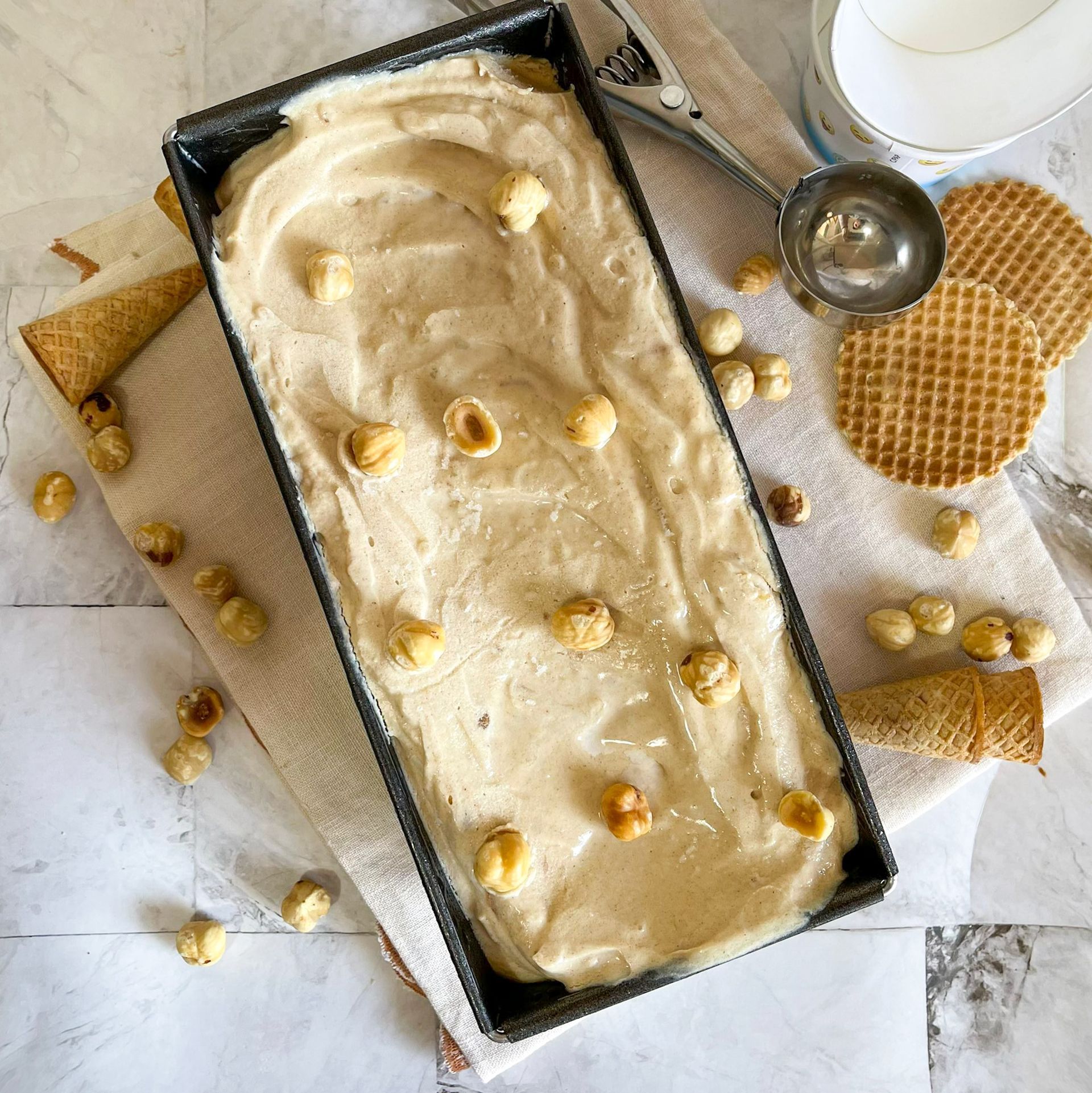 Un contenitore di gelato con sopra delle noci è appoggiato su un tavolo.