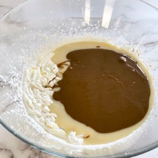 Una ciotola di vetro piena di un liquido marrone e panna montata.