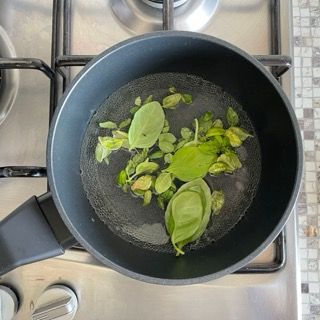 Una pentola piena d'acqua e foglie verdi su un fornello