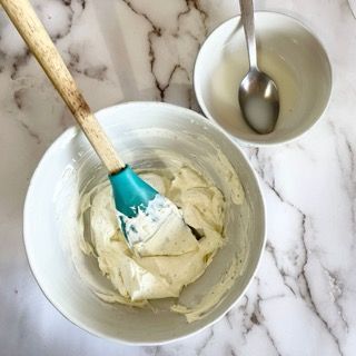 Una ciotola di glassa con una spatola e un cucchiaio dentro