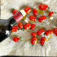 Una bottiglia di vino viene versata in un mucchio di pomodori.