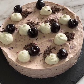 Una torta con panna montata e ciliegie sopra.