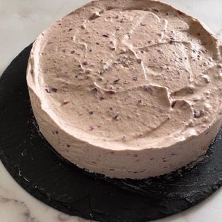 Una torta è appoggiata su un piatto nero su un tavolo.