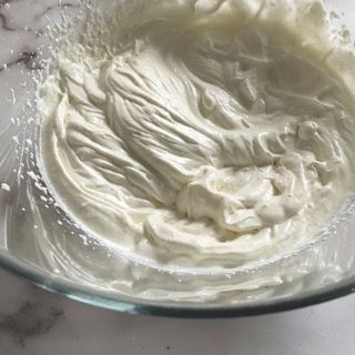 Una ciotola di panna montata è appoggiata su un tavolo.