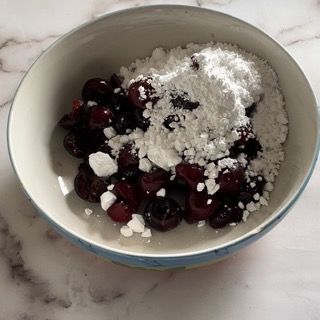 Una ciotola di ciliegie e zucchero a velo su un tavolo