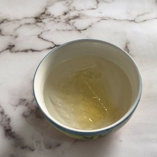 Una ciotola piena di liquido è appoggiata su una superficie di marmo.