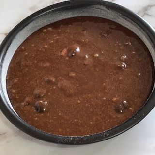 Una ciotola di salsa al cioccolato è appoggiata su un tavolo.