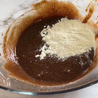 Una ciotola di vetro piena di liquido marrone e polvere bianca