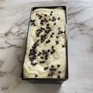 Su un tavolo c'è un pezzo di gelato con gocce di cioccolato sopra.
