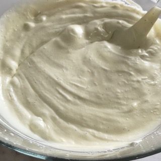 Un primo piano di una ciotola di panna montata con un cucchiaio dentro.