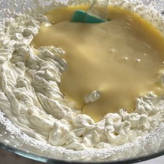 Una ciotola di panna montata con una spatola verde dentro.