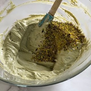 Una ciotola di glassa con una spatola e pistacchi dentro.