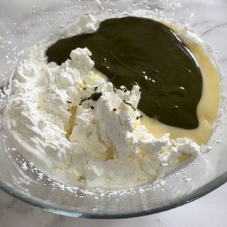 Una ciotola di vetro piena di panna montata e liquido verde.